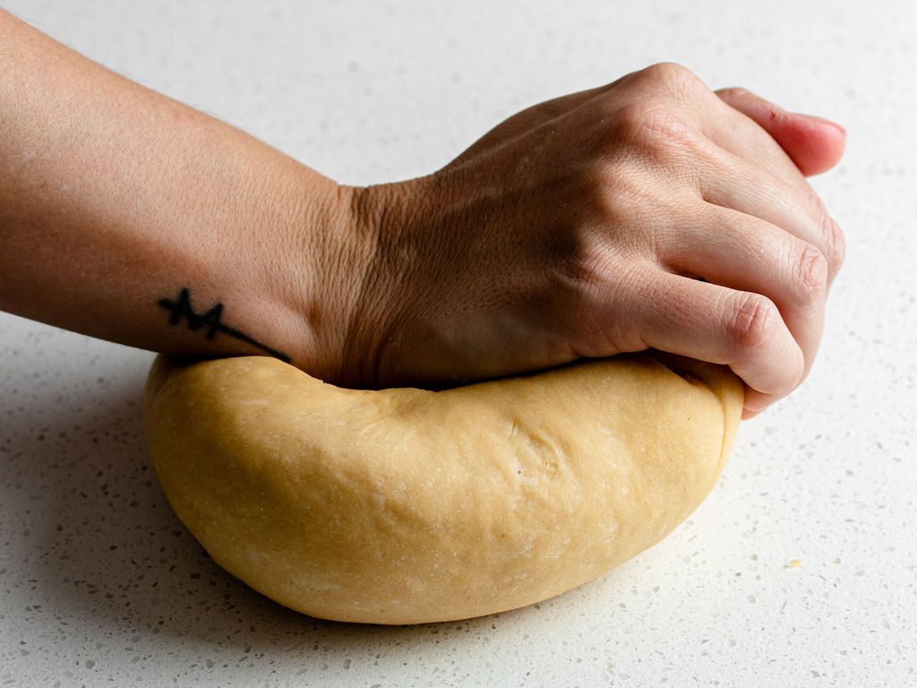 A hand kneading pasta dough.